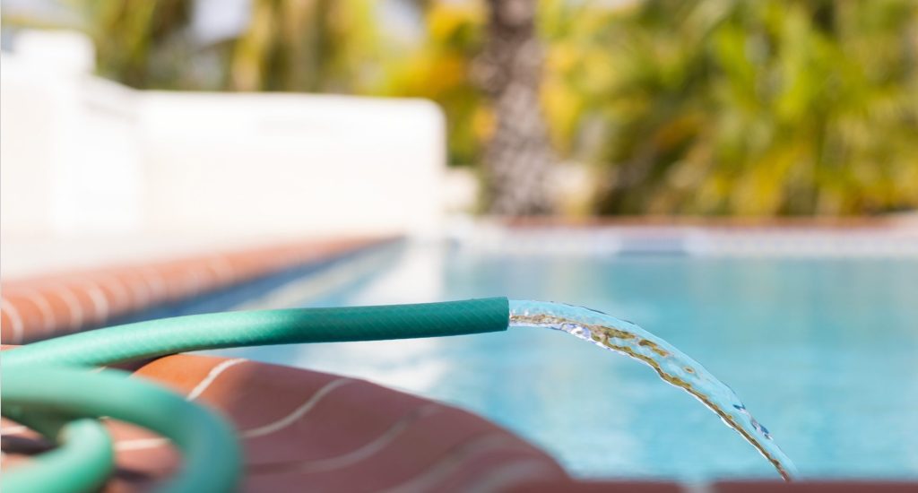 Garden hose filling a pool