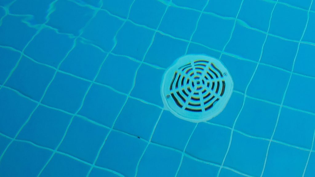 Close-up of pool drain on the floor of a swimming pool - Pool Maintenance Tips