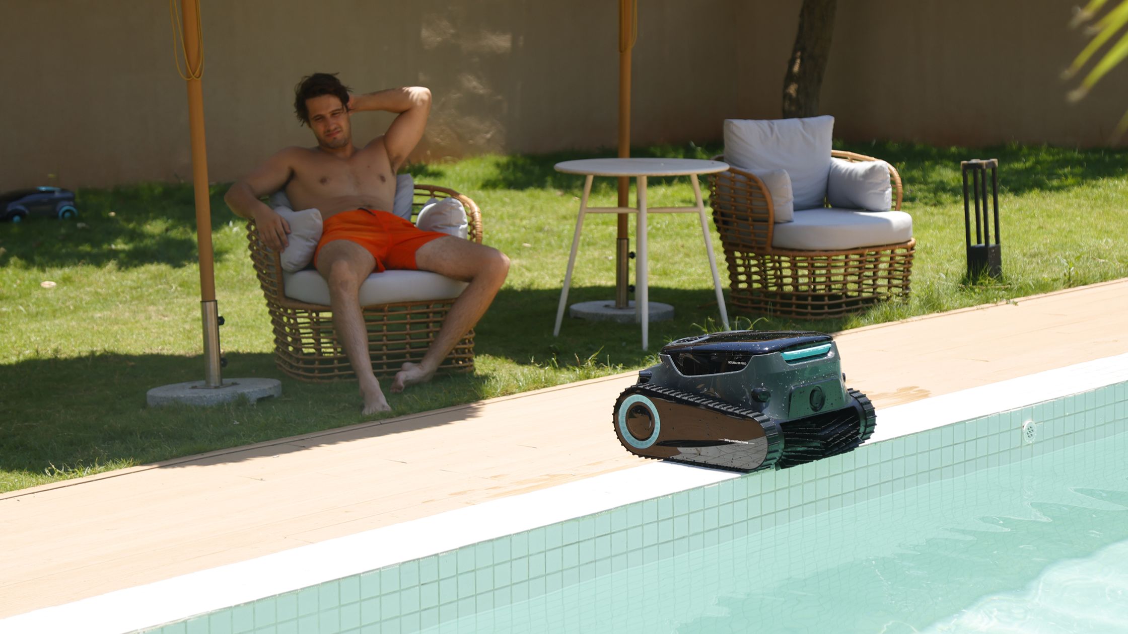 man relaxing by the pool with a cleaner nearby, ensuring pool safety for families